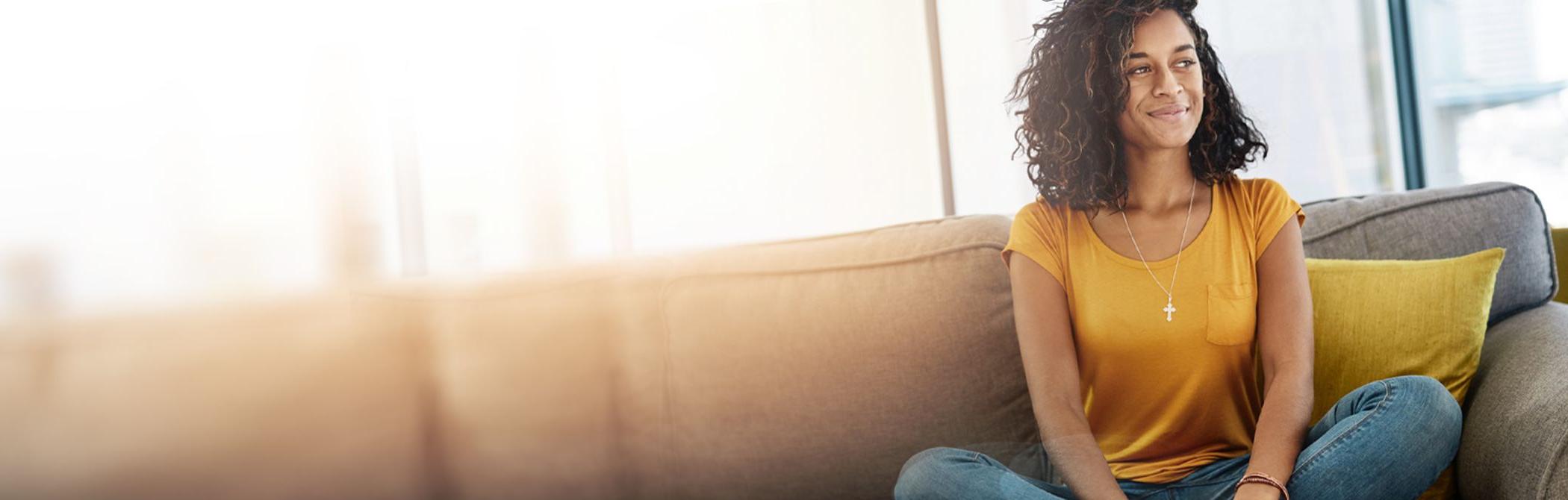 A woman smiles peacefully from her couch.